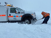 A Caltrans employee shoveling snow in front of a stuck Caltrans truck on January 10, 2023.