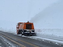 An orange Caltrans snowblower removes snow from Conway Summit on U.S. 395 on January 11, 2023.