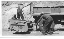 An undated black and white picture of highway crews spreading chips on the pavement.