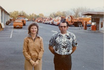 A photograph of part of the District Office parking lot with two unnamed employees. (Undated)