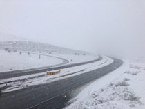 Snow falls on State Route 58 near Tehachapi in December, 2021. The road is closed and the highway is completely empty.