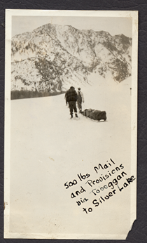An undated black and white image of mail loaded on a toboggan to be delivered to Silver Lake. Writing on the image reads "500 lbs. mail and provisions via toboggan to Silver Lake."