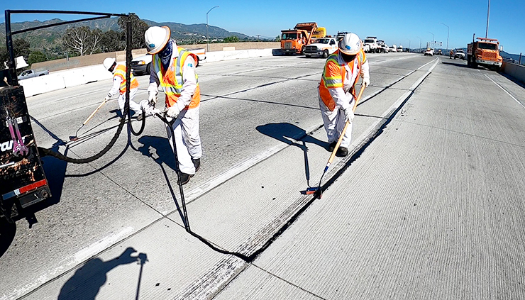 Photo of three Caltrans maintenance workers sealing cracks on Highway 99.