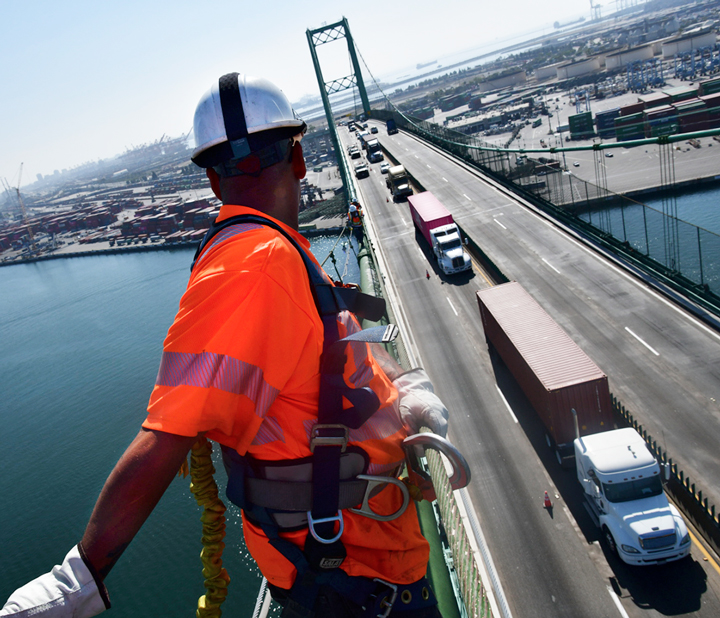 Traffic and Port of Long Beach are viewed from high up, as Caltrans workers inspect the Vincent Thomas Bridge for needed SB 1 repairs.